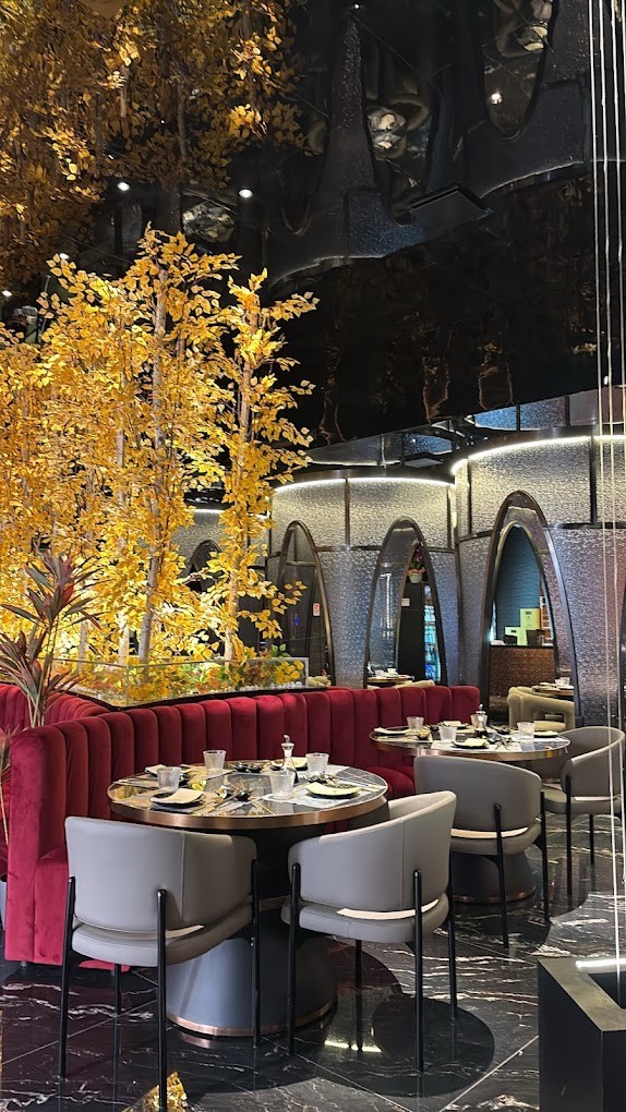 La sala principale con poltrone in velluto bordeaux e alberi dalle foglie dorate