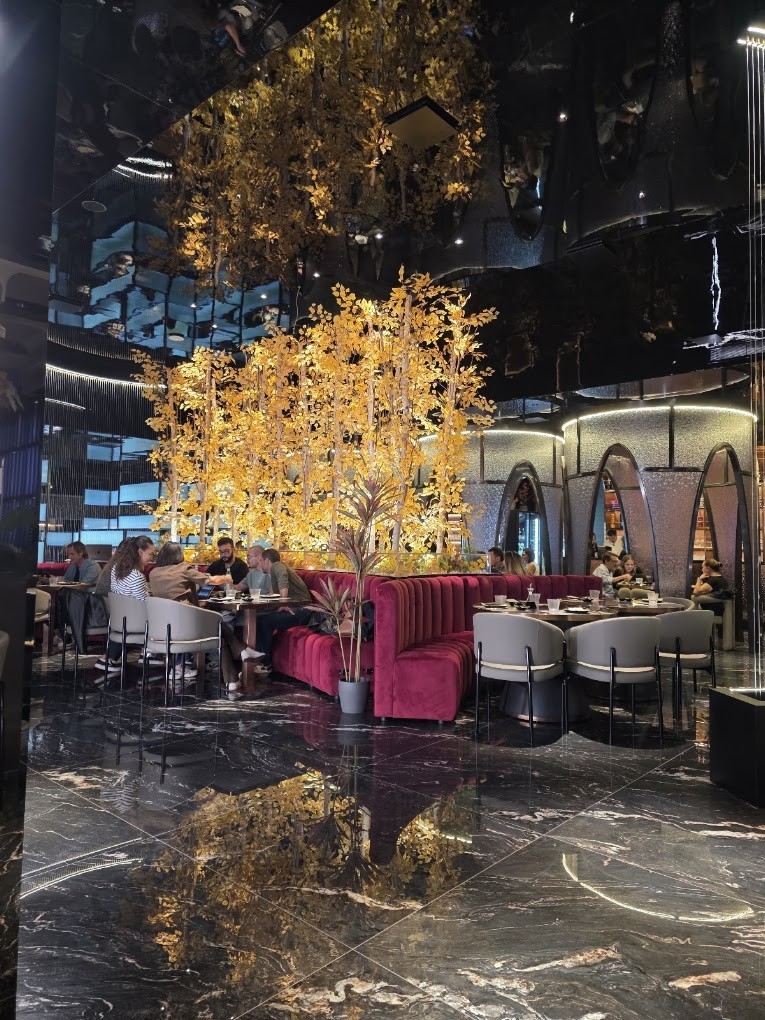 Ospiti a cena nella sala, tra divani bordeaux e marmo nero